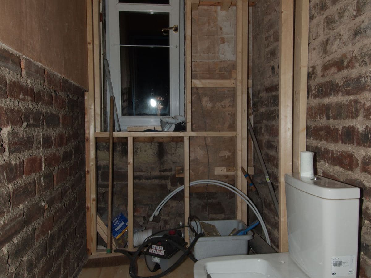 Baño en obra durante una reforma, con alicatado nuevo y sanitarios pendientes de instalar