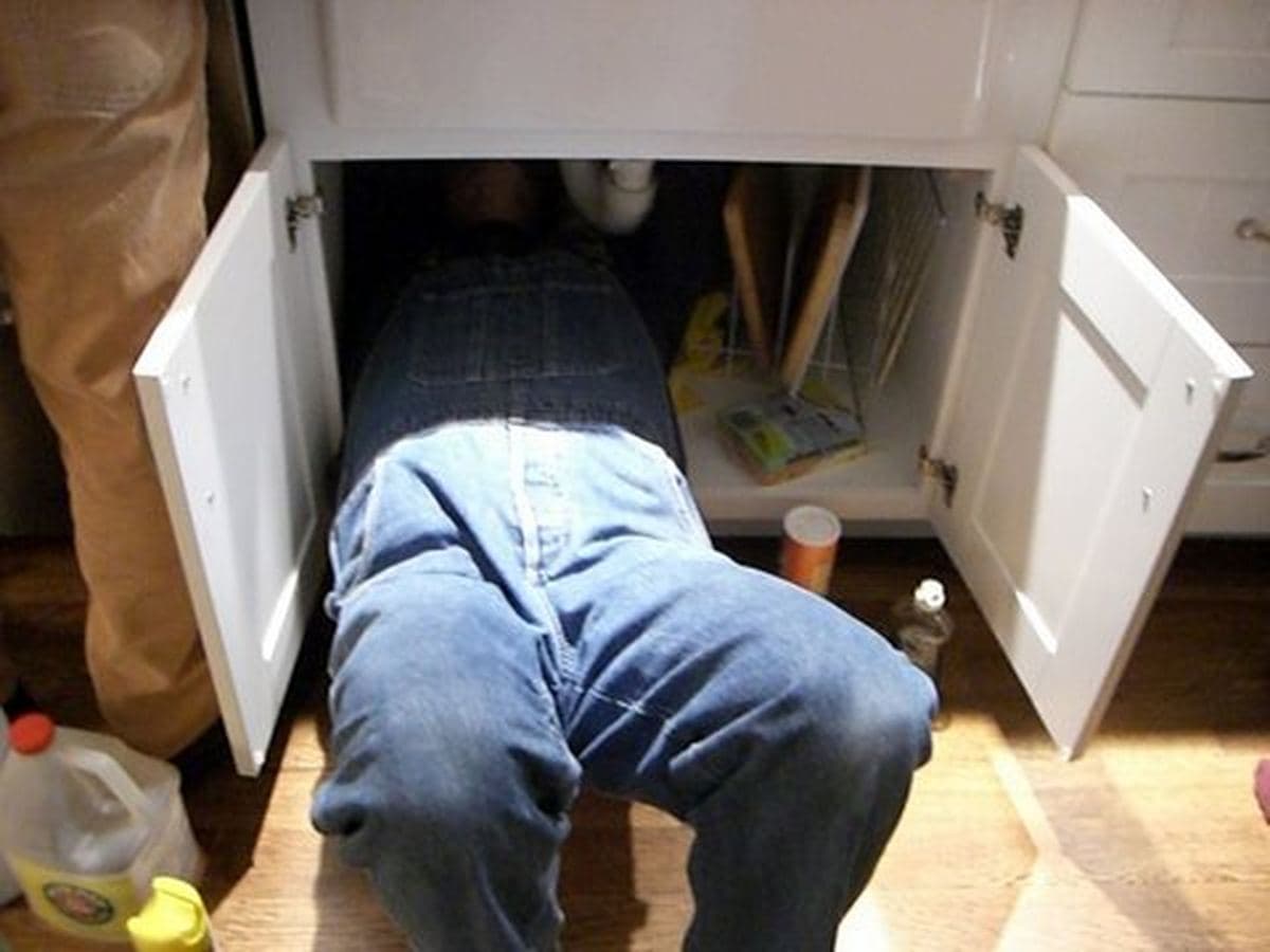 Fontanero reparando las tuberías bajo el fregadero de una cocina